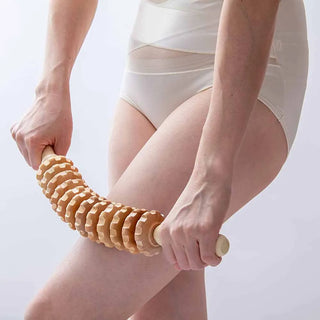 Wooden maderoterapia roller being worked along the back of the thigh